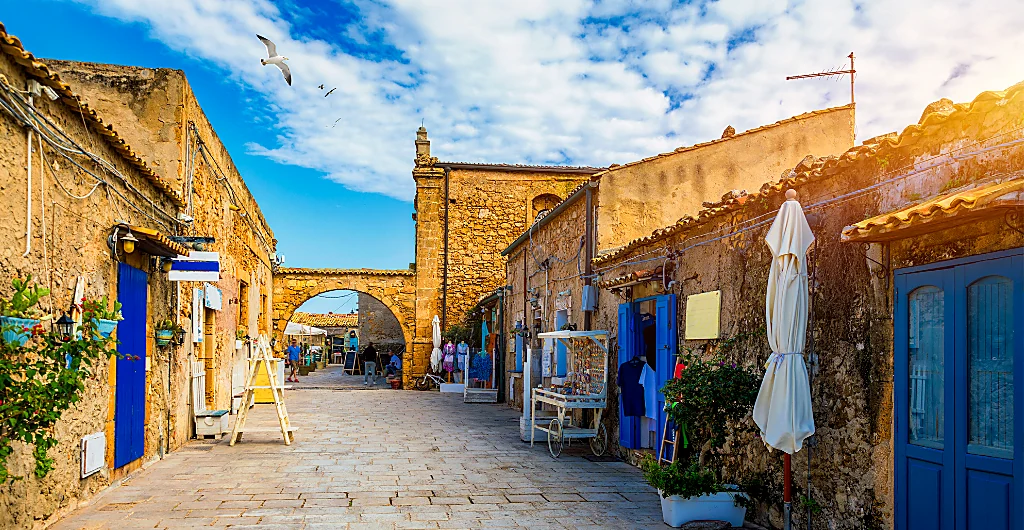 Vicolo del borgo di Marzamemi con case in pietra e porte blu